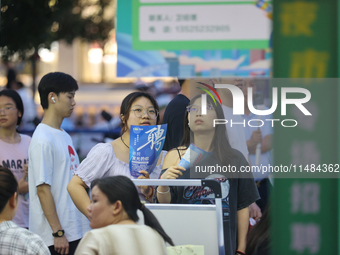 Job seekers are looking for information at a night market recruitment fair in Sanmenxia, China, on August 16, 2024. (