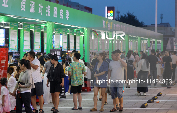 Job seekers are looking for information at a night market recruitment fair in Sanmenxia, China, on August 16, 2024. 