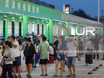 Job seekers are looking for information at a night market recruitment fair in Sanmenxia, China, on August 16, 2024. (