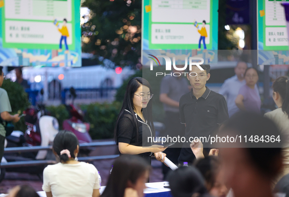 Job seekers are looking for information at a night market recruitment fair in Sanmenxia, China, on August 16, 2024. 