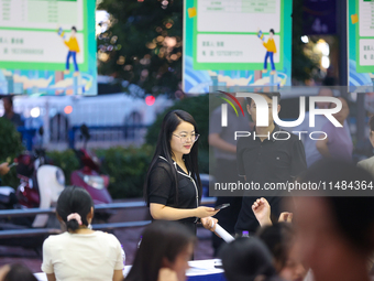 Job seekers are looking for information at a night market recruitment fair in Sanmenxia, China, on August 16, 2024. (