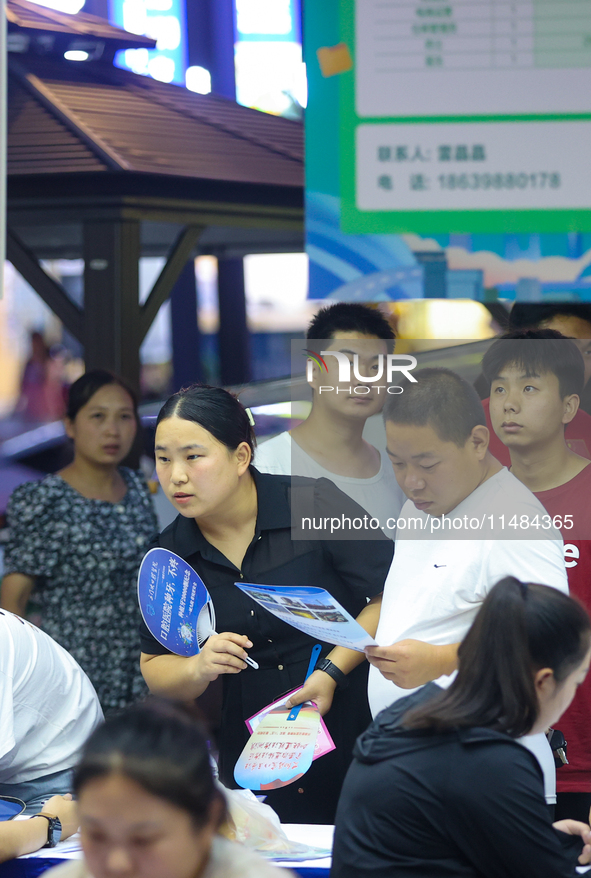 Job seekers are looking for information at a night market recruitment fair in Sanmenxia, China, on August 16, 2024. 