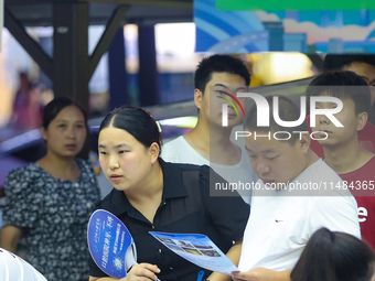 Job seekers are looking for information at a night market recruitment fair in Sanmenxia, China, on August 16, 2024. (