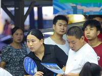 Job seekers are looking for information at a night market recruitment fair in Sanmenxia, China, on August 16, 2024. (