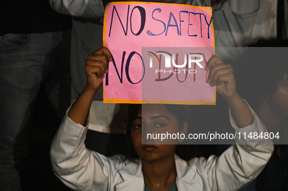 A medical professional is holding a placard in a protest condemning the rape and murder of a trainee medic at a hospital in Kolkata, in fron...