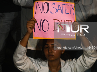 A medical professional is holding a placard in a protest condemning the rape and murder of a trainee medic at a hospital in Kolkata, in fron...