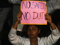 A medical professional is holding a placard in a protest condemning the rape and murder of a trainee medic at a hospital in Kolkata, in fron...