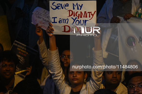 A medical professional is holding a placard in a protest condemning the rape and murder of a trainee medic at a hospital in Kolkata, in fron...