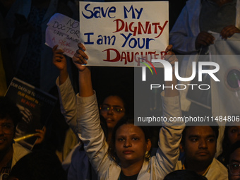 A medical professional is holding a placard in a protest condemning the rape and murder of a trainee medic at a hospital in Kolkata, in fron...