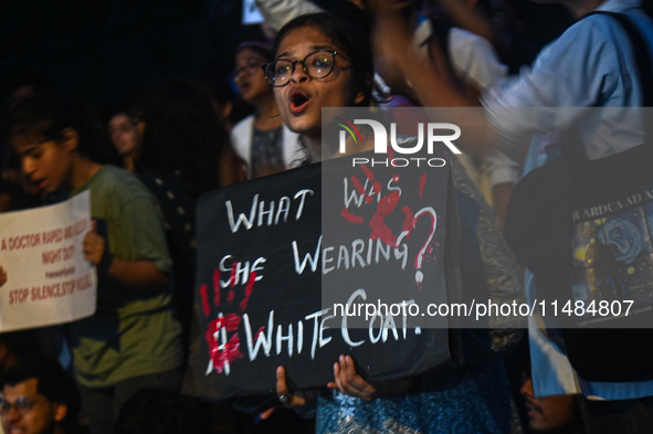 A medical professional is holding a placard in a protest condemning the rape and murder of a trainee medic at a hospital in Kolkata, in fron...