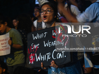 A medical professional is holding a placard in a protest condemning the rape and murder of a trainee medic at a hospital in Kolkata, in fron...