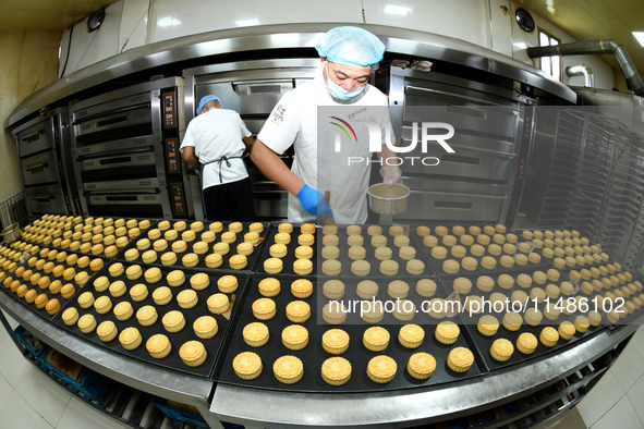 A worker is producing mooncakes at a food workshop in Hai'an, Jiangsu province, China, on August 16, 2024. 