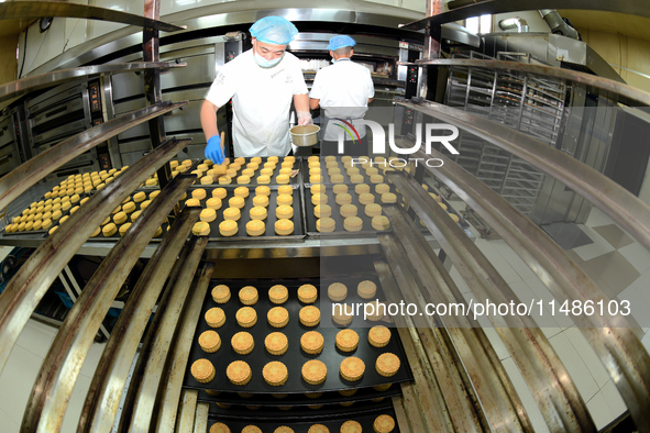 A worker is producing mooncakes at a food workshop in Hai'an, Jiangsu province, China, on August 16, 2024. 