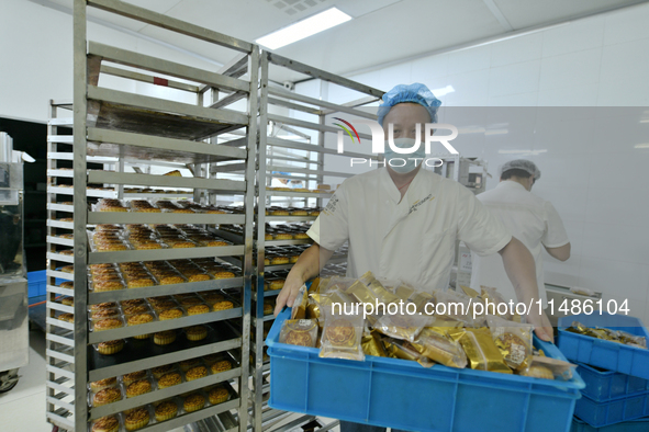 A worker is producing mooncakes at a food workshop in Hai'an, Jiangsu province, China, on August 16, 2024. 