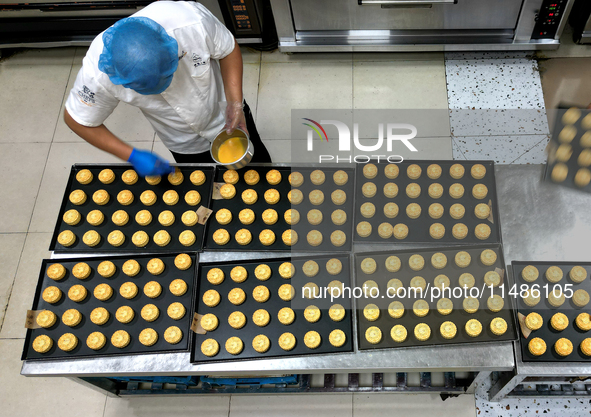 A worker is producing mooncakes at a food workshop in Hai'an, Jiangsu province, China, on August 16, 2024. 