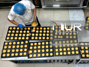 A worker is producing mooncakes at a food workshop in Hai'an, Jiangsu province, China, on August 16, 2024. (