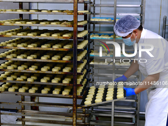 A worker is producing mooncakes at a food workshop in Hai'an, Jiangsu province, China, on August 16, 2024. (