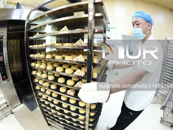 A worker is producing mooncakes at a food workshop in Hai'an, Jiangsu province, China, on August 16, 2024. (