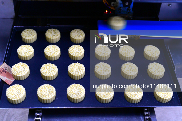 A worker is producing mooncakes at a food workshop in Hai'an, Jiangsu province, China, on August 16, 2024. 