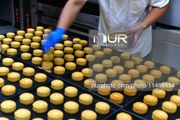 A worker is producing mooncakes at a food workshop in Hai'an, Jiangsu province, China, on August 16, 2024. 