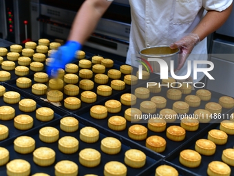 A worker is producing mooncakes at a food workshop in Hai'an, Jiangsu province, China, on August 16, 2024. (