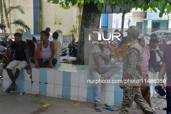 Relatives of the admitted patients are waiting under a tree at the Main Entrance of the busiest Siliguri District hospital in Siliguri, Indi...