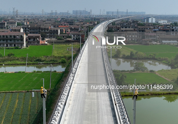 Construction workers are installing overhead contact line poles on the Fuhe River Bridge in the Beijing-Hong Kong High-speed Railway Nanchan...