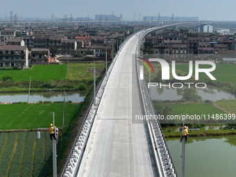 Construction workers are installing overhead contact line poles on the Fuhe River Bridge in the Beijing-Hong Kong High-speed Railway Nanchan...