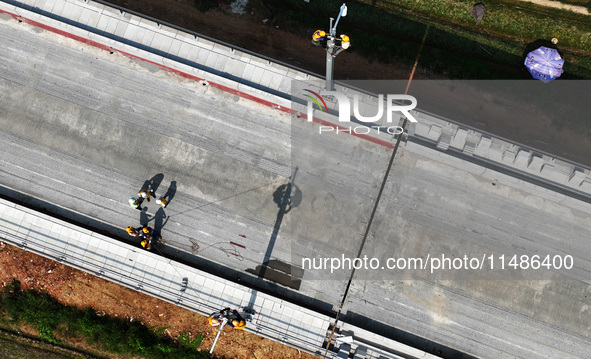 Construction workers are installing overhead contact line poles on the Fuhe River Bridge in the Beijing-Hong Kong High-speed Railway Nanchan...