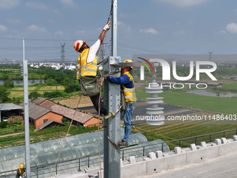 Construction workers are installing overhead contact line poles on the Fuhe River Bridge in the Beijing-Hong Kong High-speed Railway Nanchan...