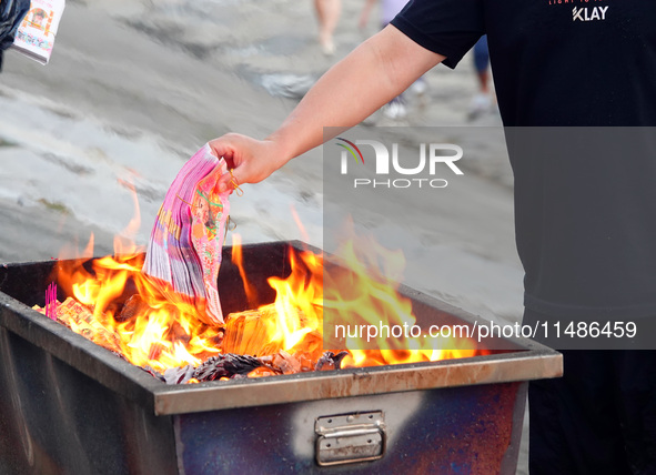 People are burning paper money to offer sacrifices to their ancestors during the Hungry Ghost Festival in Yichang, China, on August 16, 2024...