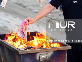 People are burning paper money to offer sacrifices to their ancestors during the Hungry Ghost Festival in Yichang, China, on August 16, 2024...