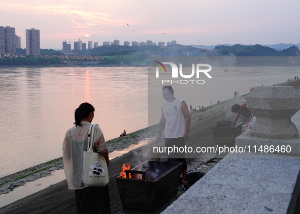 People are burning paper money to offer sacrifices to their ancestors during the Hungry Ghost Festival in Yichang, China, on August 16, 2024...