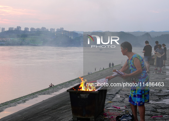 People are burning paper money to offer sacrifices to their ancestors during the Hungry Ghost Festival in Yichang, China, on August 16, 2024...