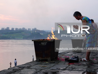 People are burning paper money to offer sacrifices to their ancestors during the Hungry Ghost Festival in Yichang, China, on August 16, 2024...