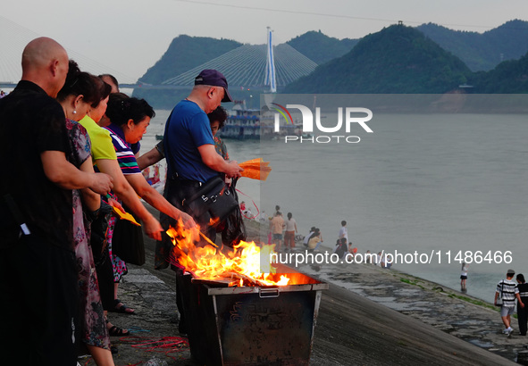 People are burning paper money to offer sacrifices to their ancestors during the Hungry Ghost Festival in Yichang, China, on August 16, 2024...