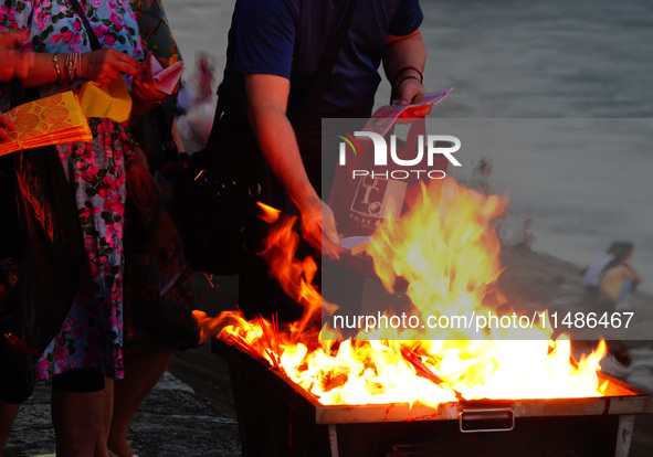 People are burning paper money to offer sacrifices to their ancestors during the Hungry Ghost Festival in Yichang, China, on August 16, 2024...