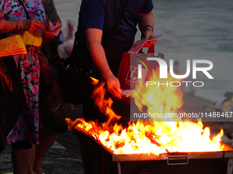 People are burning paper money to offer sacrifices to their ancestors during the Hungry Ghost Festival in Yichang, China, on August 16, 2024...