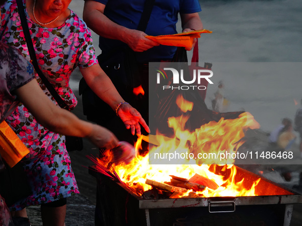 People are burning paper money to offer sacrifices to their ancestors during the Hungry Ghost Festival in Yichang, China, on August 16, 2024...