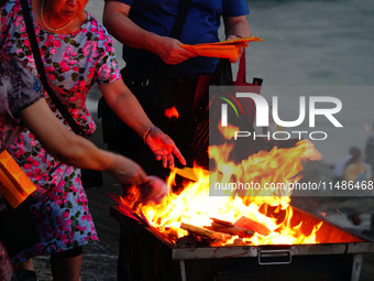 People are burning paper money to offer sacrifices to their ancestors during the Hungry Ghost Festival in Yichang, China, on August 16, 2024...