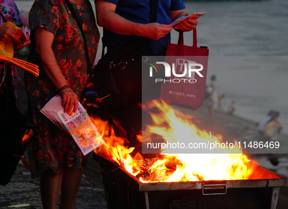 People are burning paper money to offer sacrifices to their ancestors during the Hungry Ghost Festival in Yichang, China, on August 16, 2024...