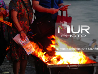 People are burning paper money to offer sacrifices to their ancestors during the Hungry Ghost Festival in Yichang, China, on August 16, 2024...