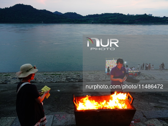 People are burning paper money to offer sacrifices to their ancestors during the Hungry Ghost Festival in Yichang, China, on August 16, 2024...