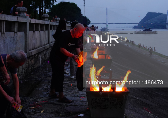 People are burning paper money to offer sacrifices to their ancestors during the Hungry Ghost Festival in Yichang, China, on August 16, 2024...