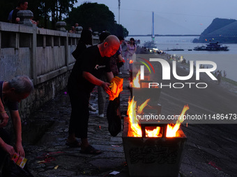 People are burning paper money to offer sacrifices to their ancestors during the Hungry Ghost Festival in Yichang, China, on August 16, 2024...