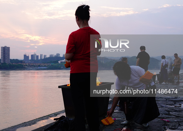 People are burning paper money to offer sacrifices to their ancestors during the Hungry Ghost Festival in Yichang, China, on August 16, 2024...