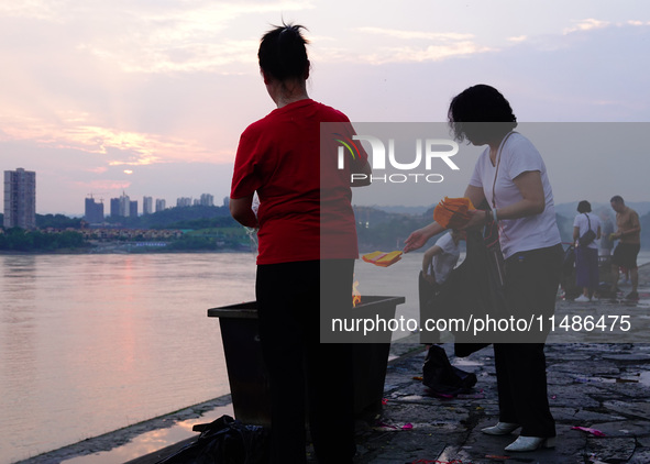 People are burning paper money to offer sacrifices to their ancestors during the Hungry Ghost Festival in Yichang, China, on August 16, 2024...