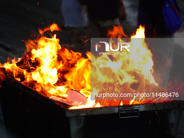 People are burning paper money to offer sacrifices to their ancestors during the Hungry Ghost Festival in Yichang, China, on August 16, 2024...