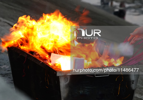 People are burning paper money to offer sacrifices to their ancestors during the Hungry Ghost Festival in Yichang, China, on August 16, 2024...