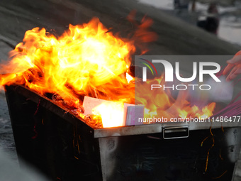 People are burning paper money to offer sacrifices to their ancestors during the Hungry Ghost Festival in Yichang, China, on August 16, 2024...